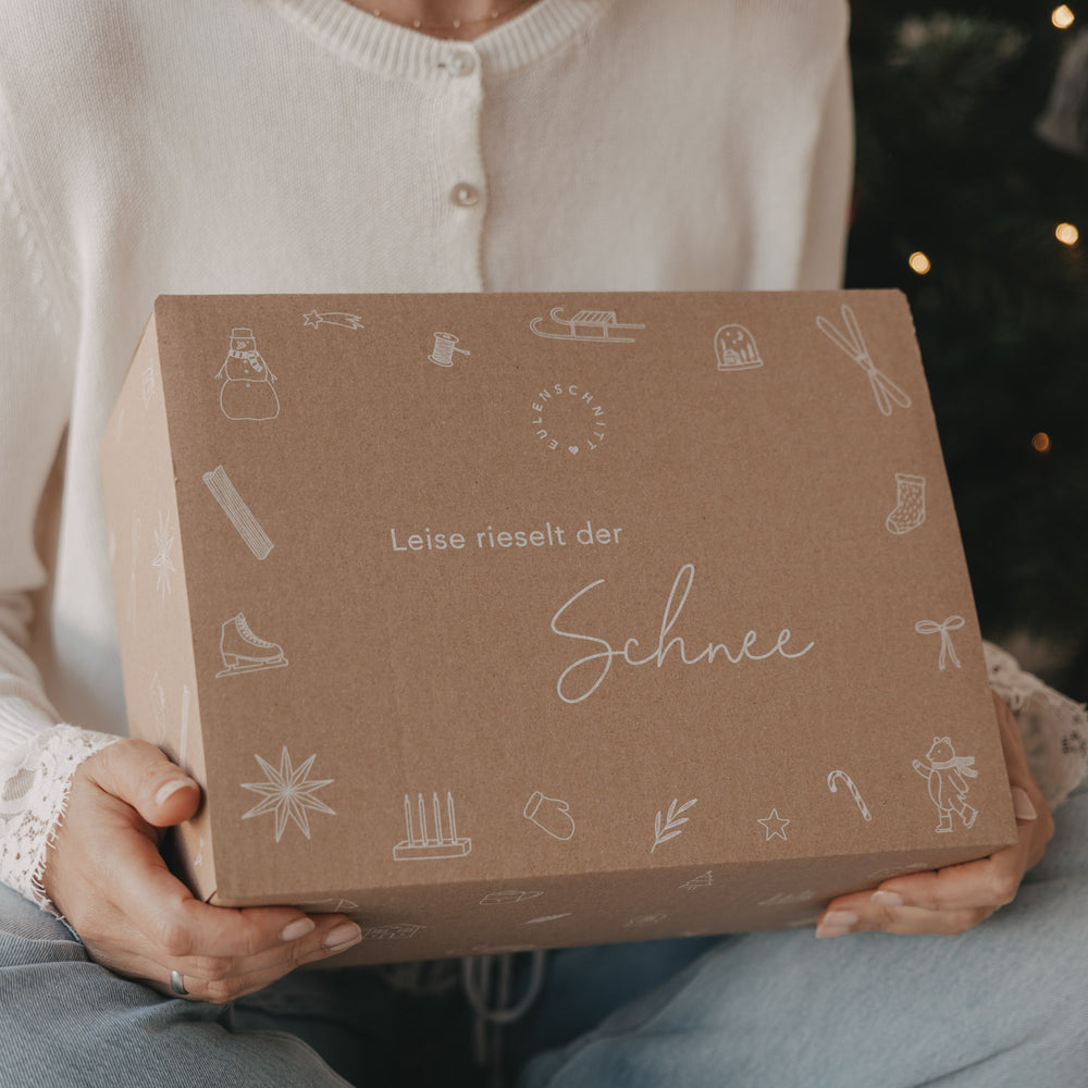 Detailaufnahme der limitierten Winter-Überraschungsbox 2026 von Eulenschnitt mit Schneemann, Schlitten, Sternen und dem Schriftzug „Leise rieselt der Schnee“.
 Kopieren
