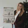 Frau präsentiert den Eulenschnitt Signature-Adventskalender neben einem beleuchteten Weihnachtsbaum.