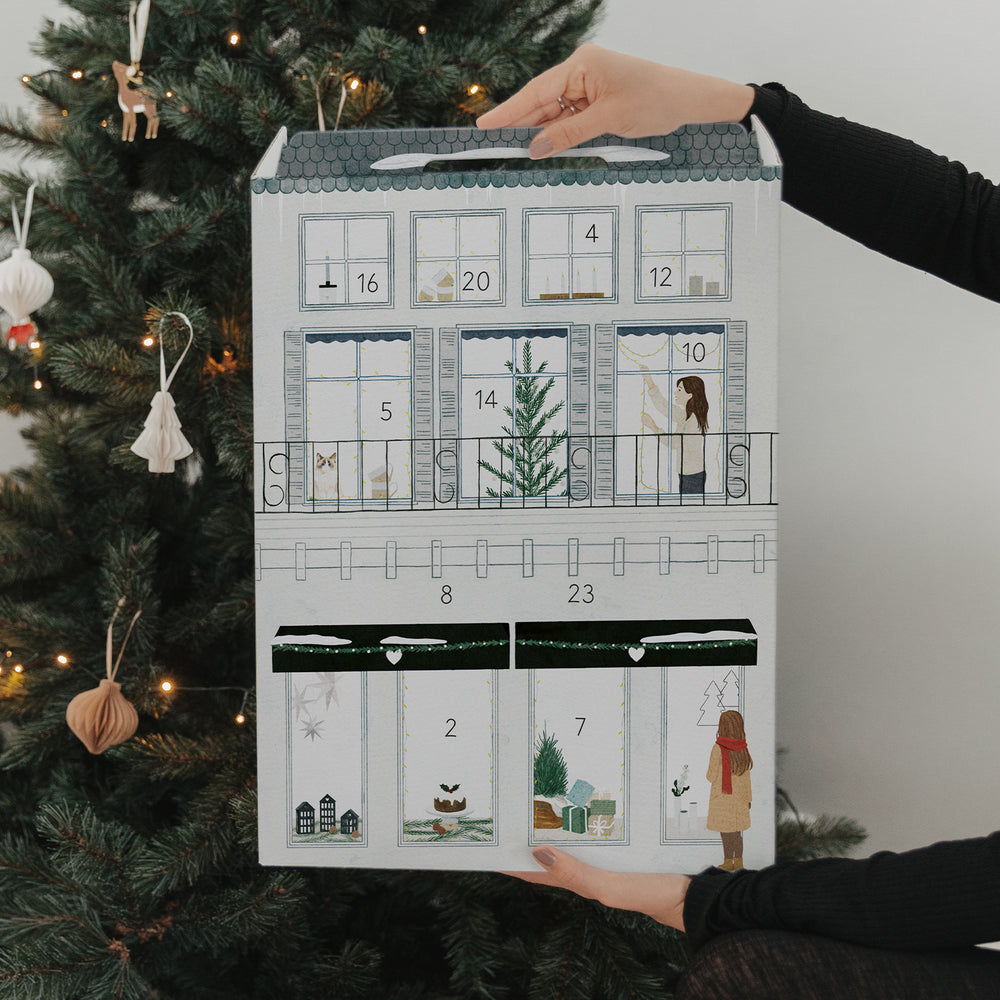 Eulenschnitt Adventskalender vor festlichem Weihnachtsbaum und Geschenken – liebevoll gestaltete Rückseite.