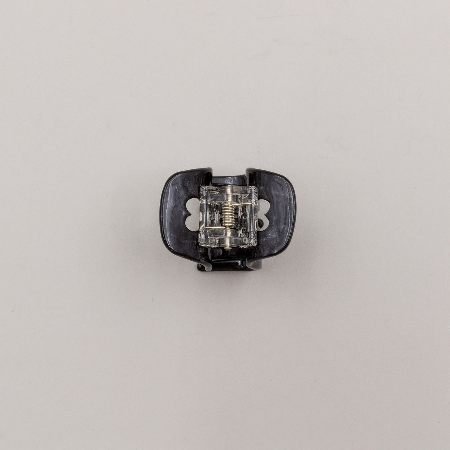 Unterseite der schwarzen Haarspange mit Metallfeder und Herz-Details – stabil und funktional.