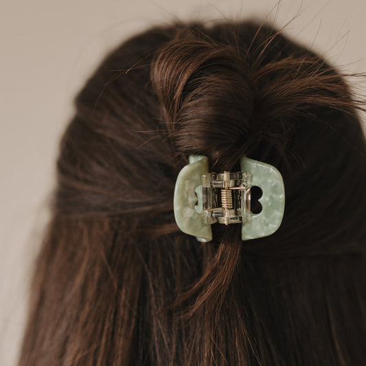 Rückansicht einer Frisur mit Haarspange klein Herz jade im Knoten – zartes Design mit ausgestanztem Herz.