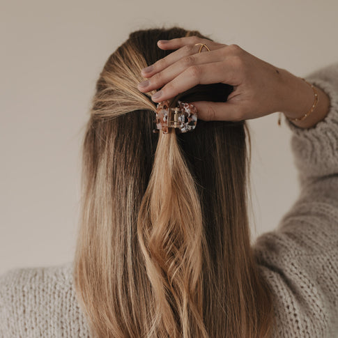 Hand fixiert eine Haarsträhne mit der kleinen Herzspange Almond – eleganter Alltagsmoment