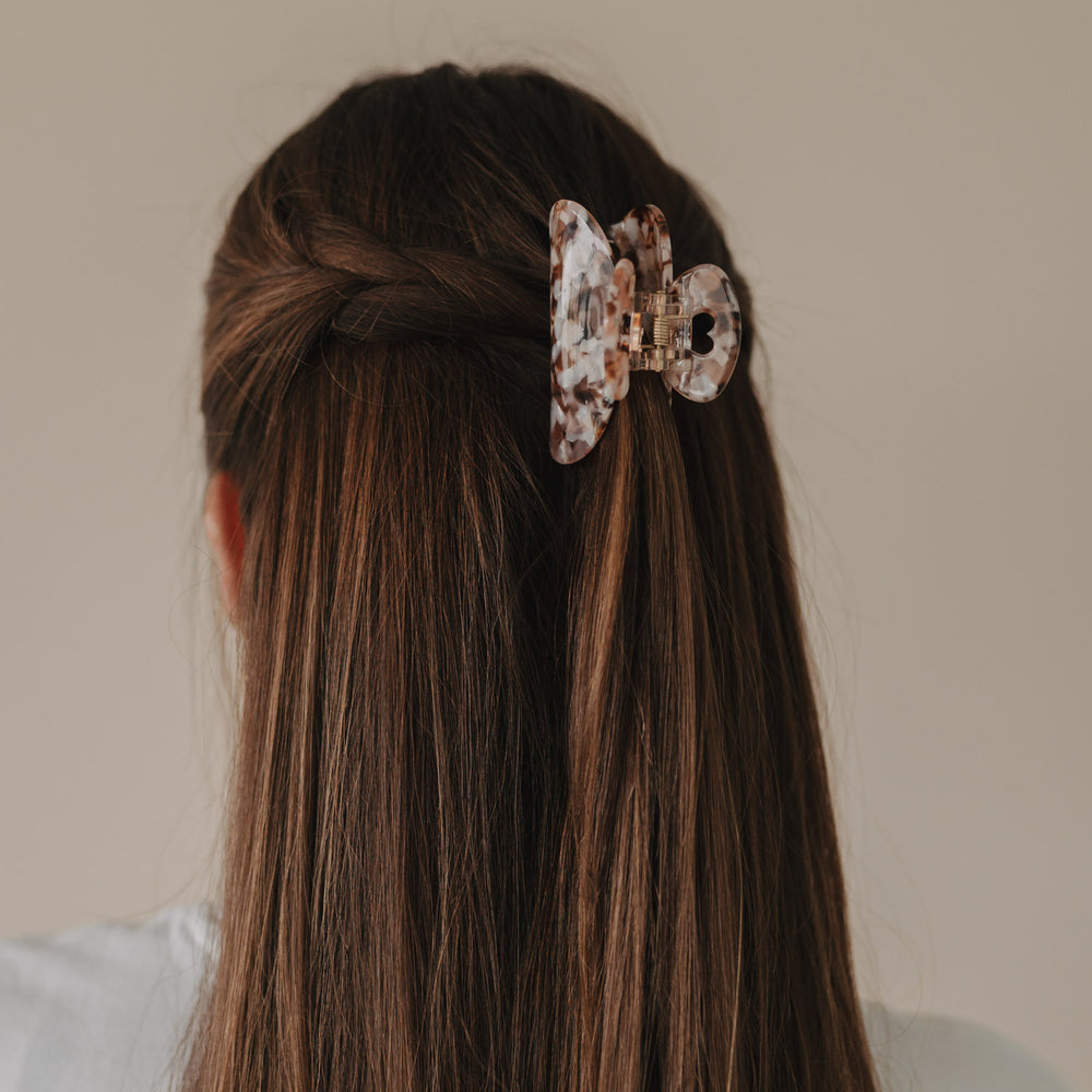 Rückansicht einer halboffenen Frisur mit geflochtenen Seiten und großer Haarspange Herz Almond.