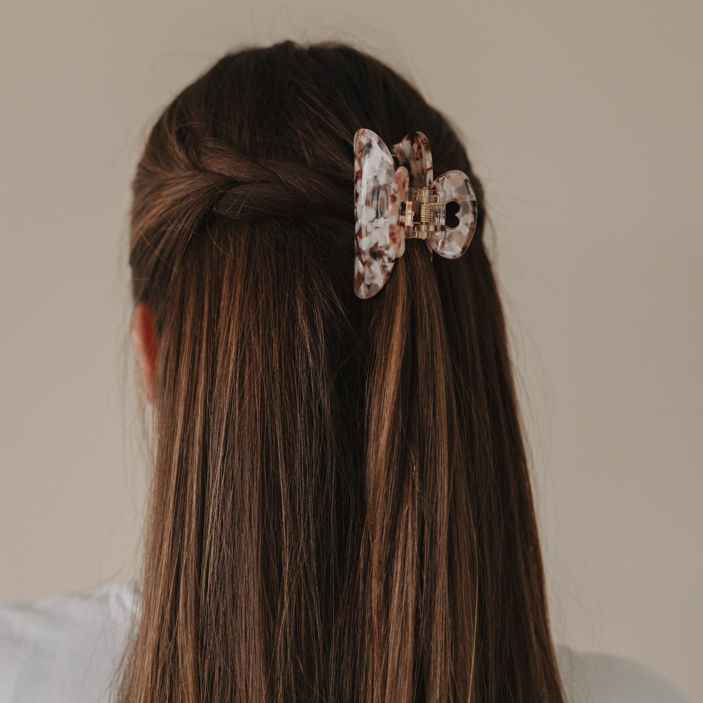 Rückansicht einer halboffenen Frisur mit geflochtenen Seiten und großer Haarspange Herz Almond.