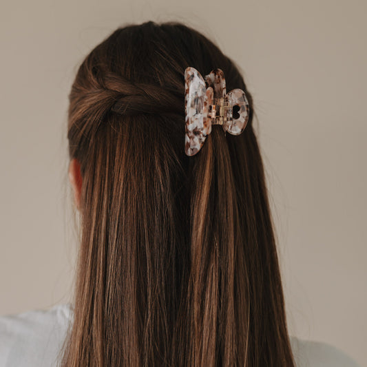 Rückansicht einer halboffenen Frisur mit geflochtenen Seiten und großer Haarspange Herz Almond.