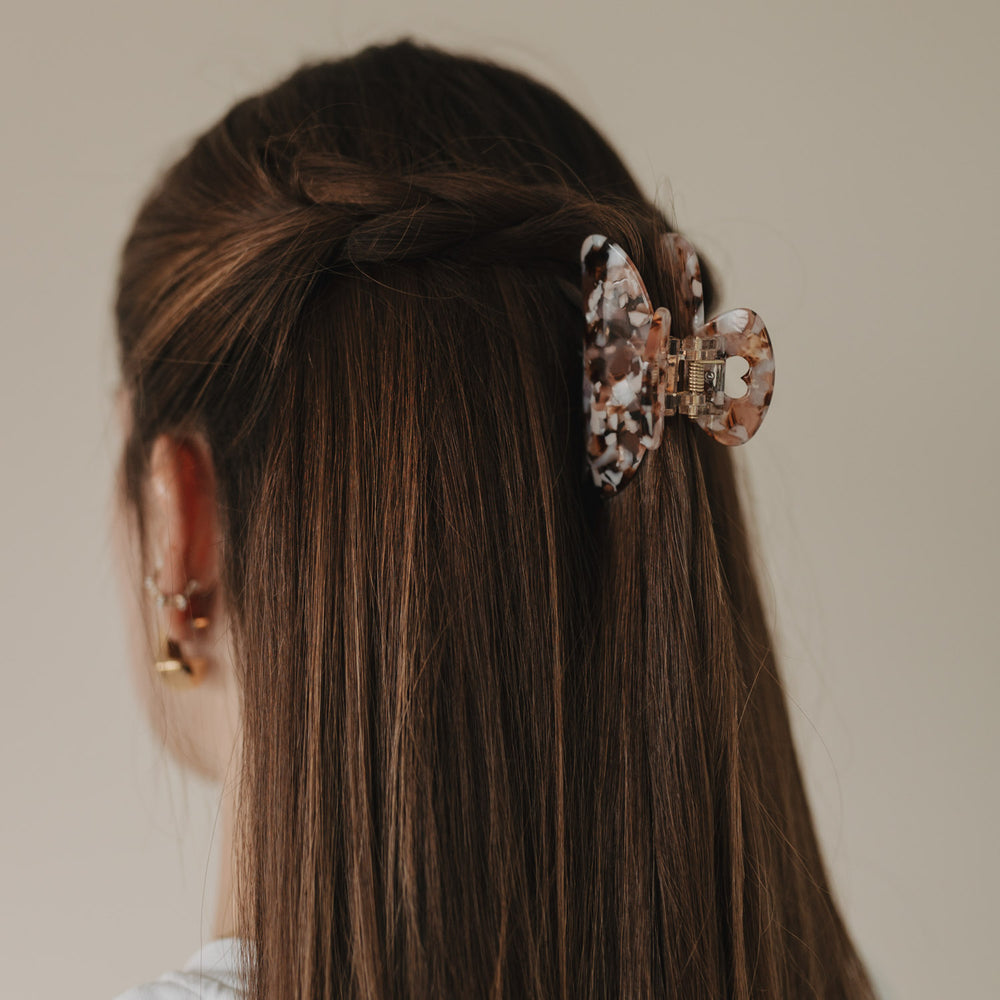 Große Haarspange Herz Almond fixiert halboffene Frisur in glattem, braunem Haar – seitlicher Blick.