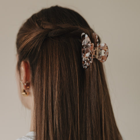 Große Haarspange Herz Almond fixiert halboffene Frisur in glattem, braunem Haar – seitlicher Blick.
