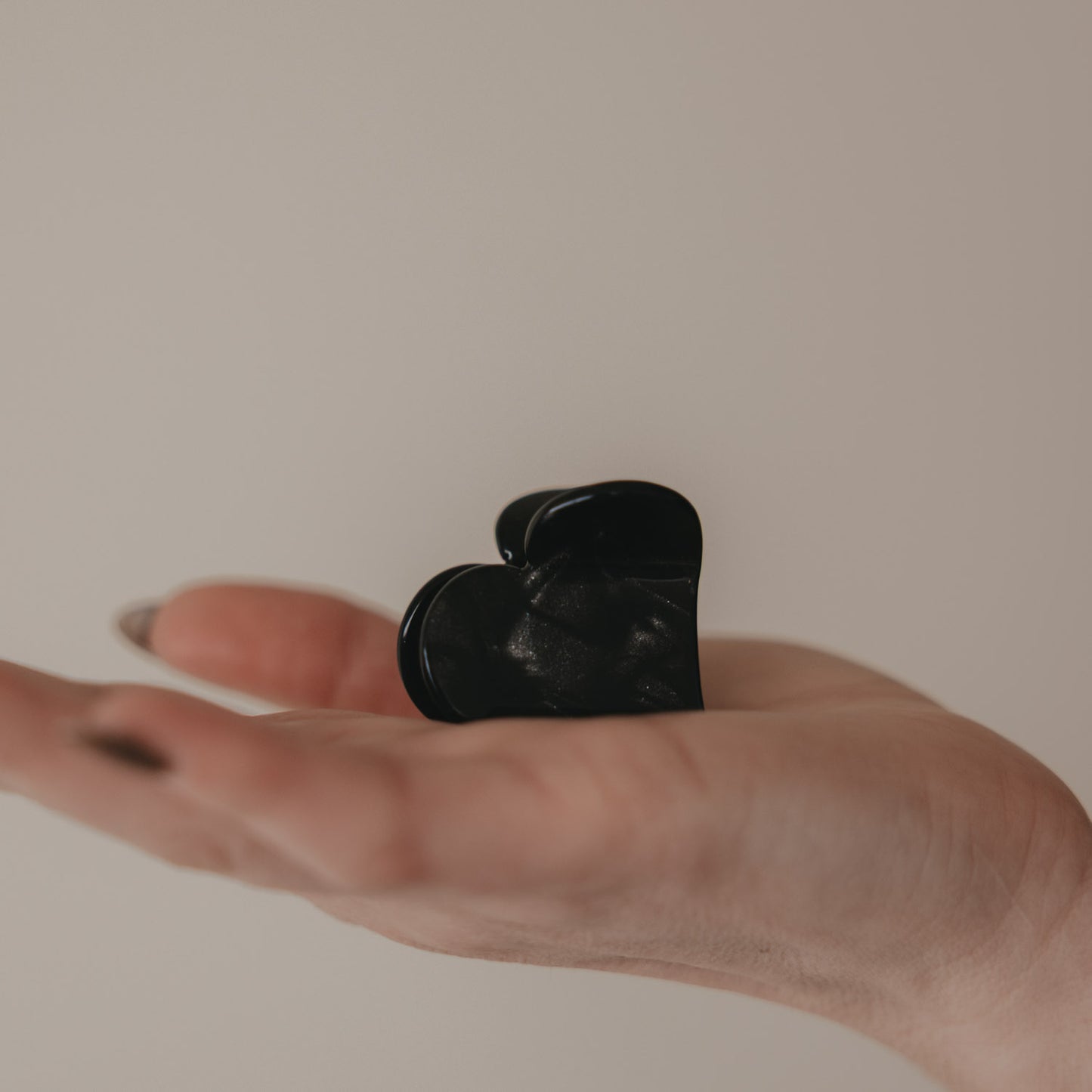 Große schwarze Haarspange in Herzform auf der Hand präsentiert