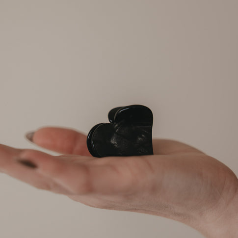 Große schwarze Haarspange in Herzform auf der Hand präsentiert
