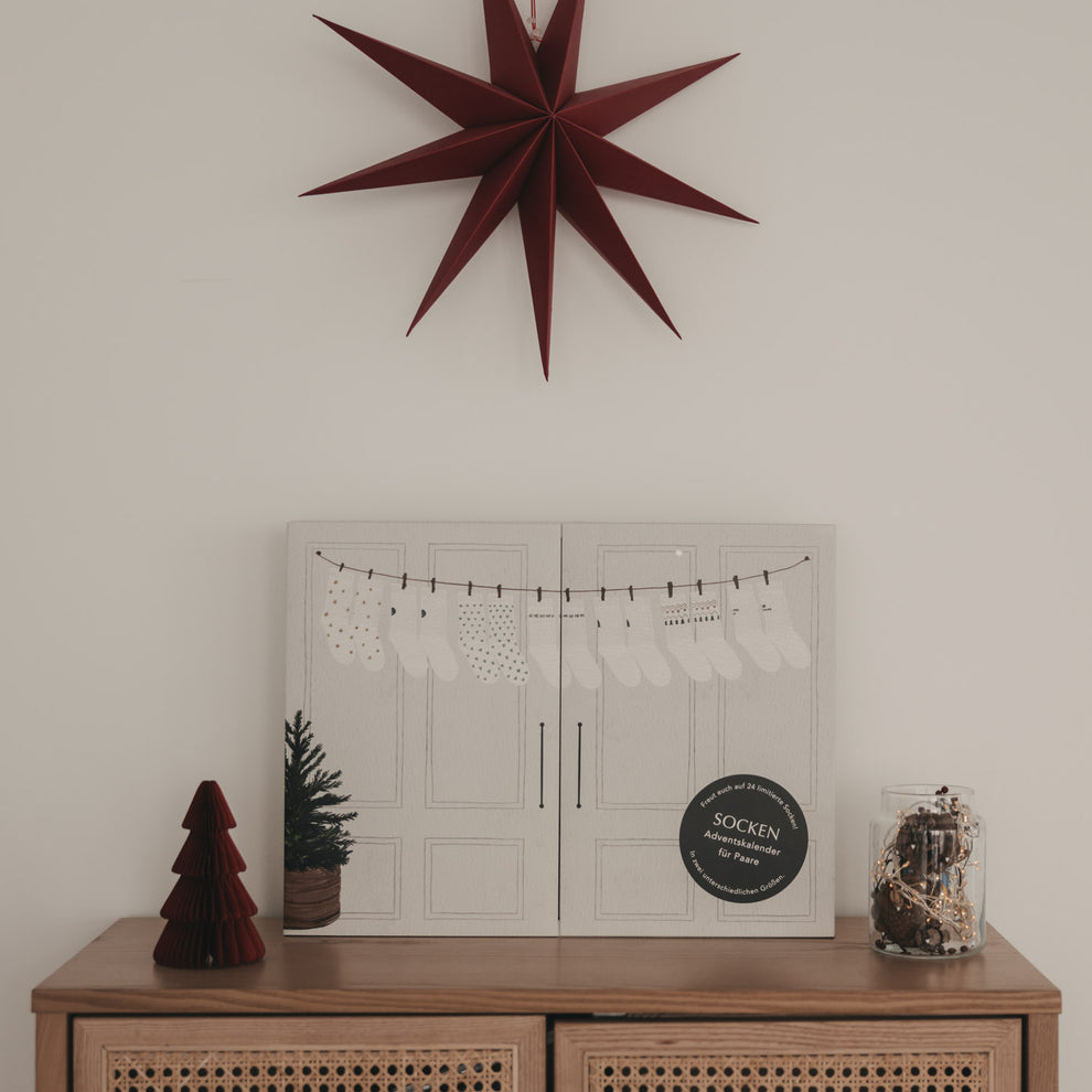 Eulenschnitt Socken-Adventskalender für Paare dekoriert mit Weihnachtsstern und Lichterkette