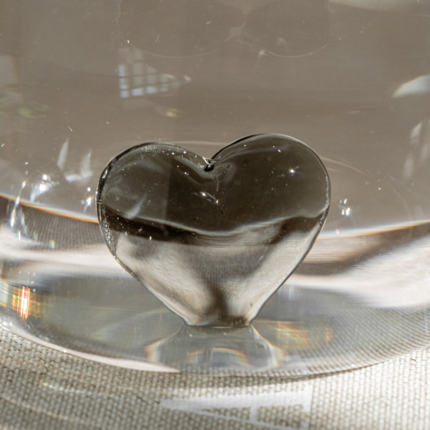 Schwarzes Herz aus Glas als Figur in einem Trinkglas, Nahaufnahme.