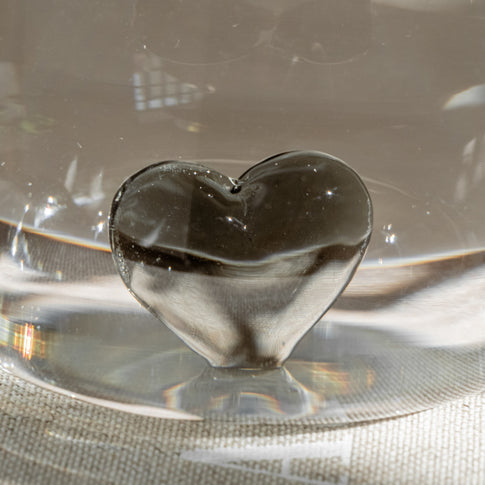 Schwarzes Herz aus Glas als Figur in einem Trinkglas, Nahaufnahme.