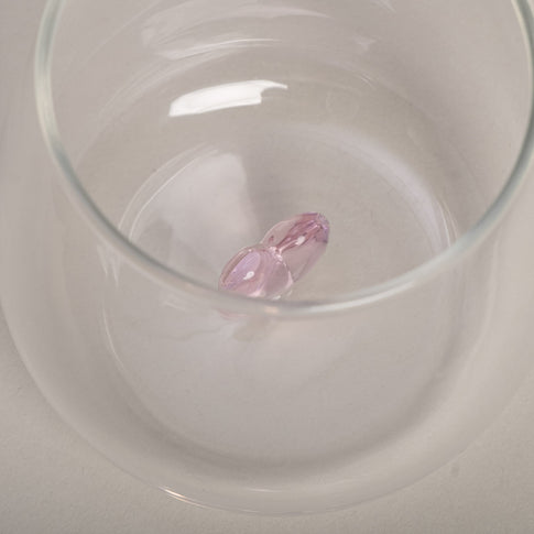 Rosa Herzfigur aus Glas im Inneren eines transparenten Trinkglases.