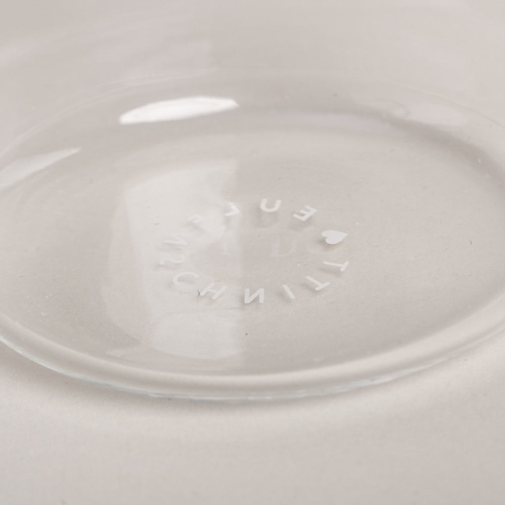 Prägung mit Eulenschnitt-Schriftzug am Glasboden, Detailaufnahme im klaren Trinkglas auf hellem Untergrund.