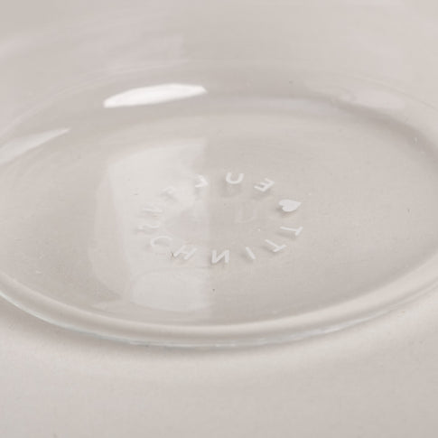 Prägung mit Eulenschnitt-Schriftzug am Glasboden, Detailaufnahme im klaren Trinkglas auf hellem Untergrund.