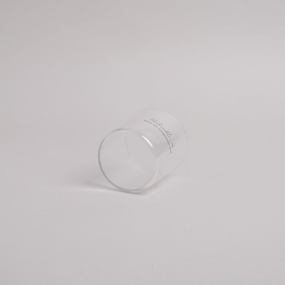 Trinkglas mit schwarzem Schriftzug „Weihnachten ist, wenn wir zusammen sind.“ – seitlich liegend fotografiert, schlichtes Weihnachtsdesign.