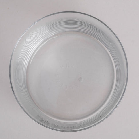 Draufsicht auf ein klares Trinkglas, geprägtem Eulenschnitt-Schriftzug am Glasboden 