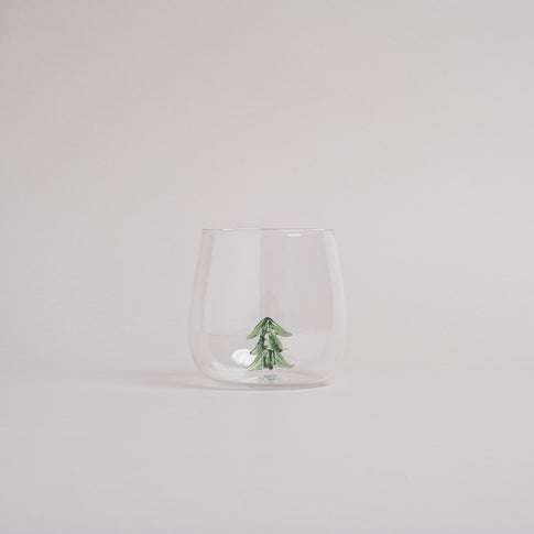 Trinkglas mit integrierter grüner Tannenfigur im Glasboden, modernes Design