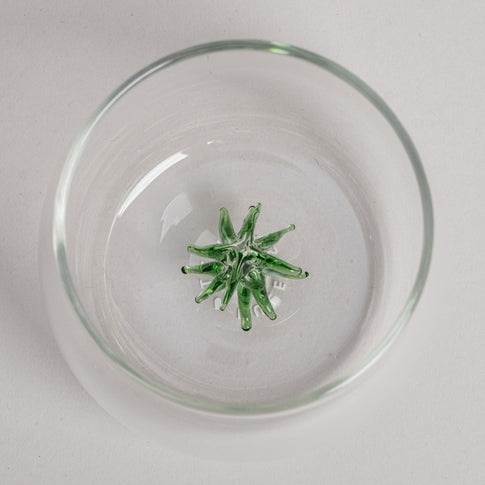 Trinkglas mit grüner Tannenfigur als dekorativem Element am Glasboden