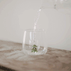 Trinkglas Tannenfigur mit eingegossener grüner Tannenbaumfigur, Wasser wird ins Glas gegossen
