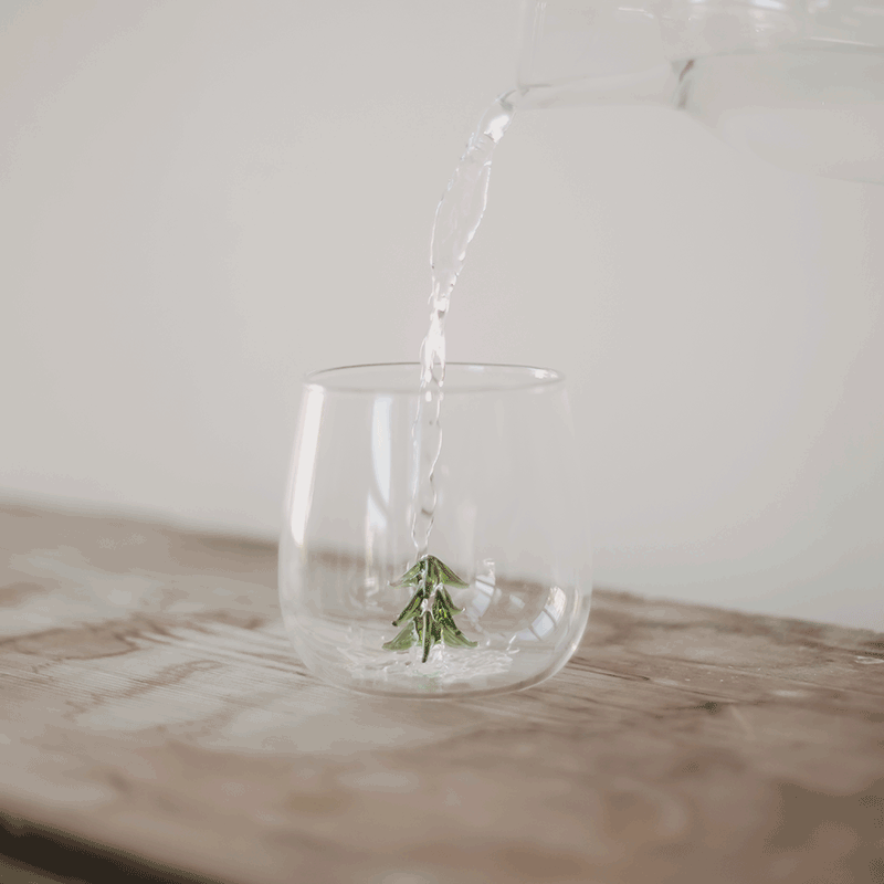 Trinkglas Tannenfigur mit eingegossener grüner Tannenbaumfigur, Wasser wird ins Glas gegossen