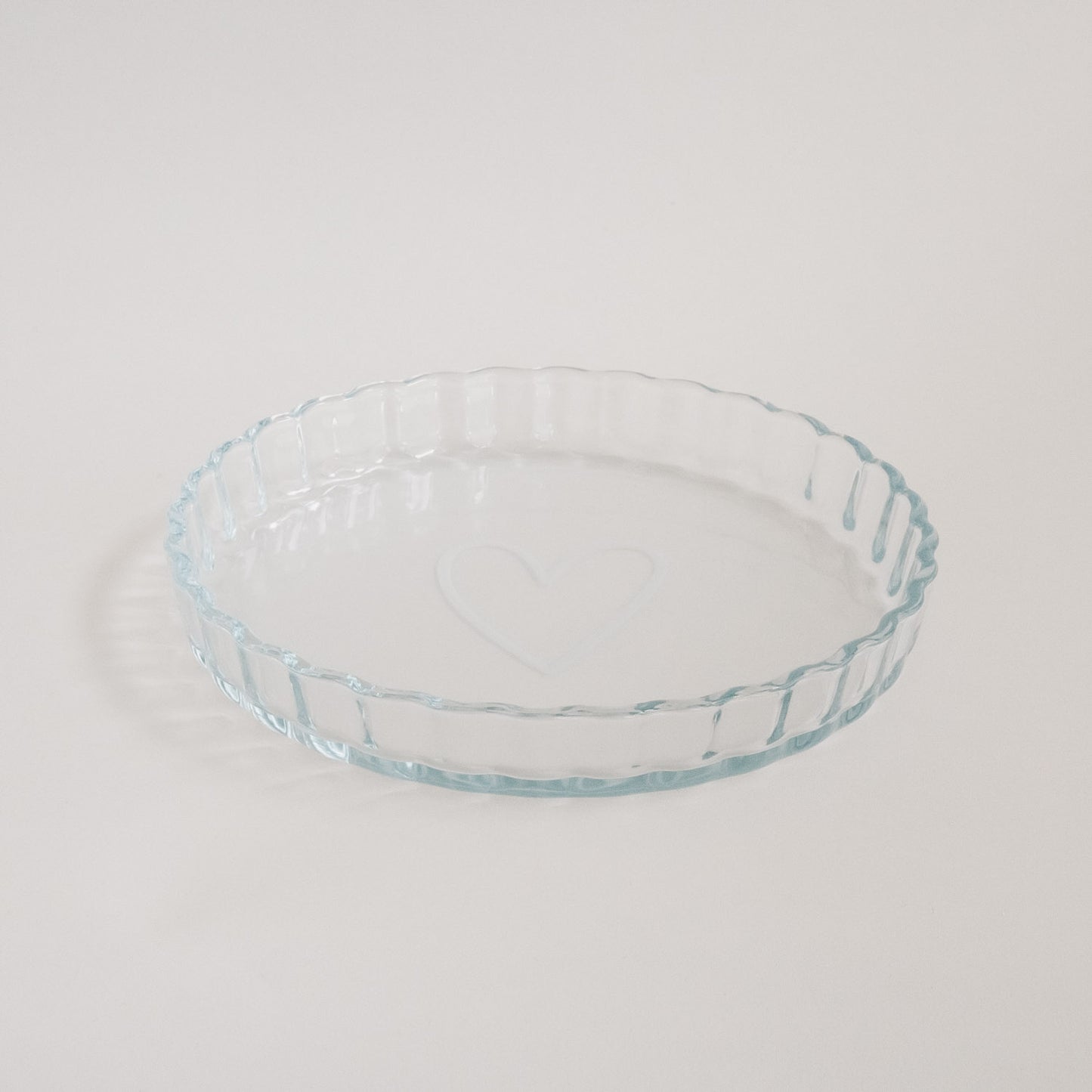 Tarteform aus Glas mit Herzmotiv, stilvoll auf hellem Untergrund fotografiert