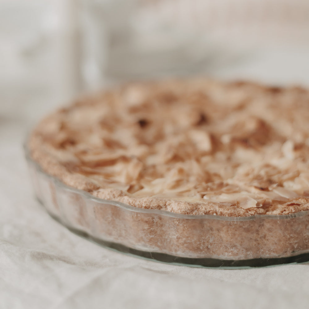 Seitenansicht einer gebackenen Tarte mit goldbrauner Kruste in transparenter Herz-Tarteform aus Glas.