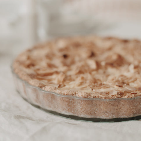 Seitenansicht einer gebackenen Tarte mit goldbrauner Kruste in transparenter Herz-Tarteform aus Glas.