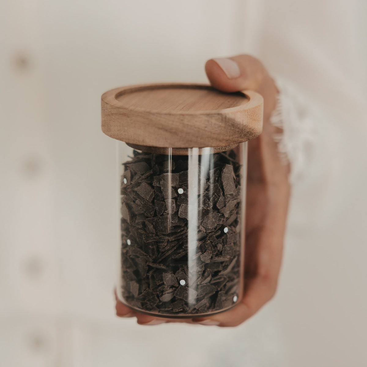 Mini Vorratsglas mit Punkten und Holzdeckel, gefüllt mit Schokoraspeln und in der Hand gehalten