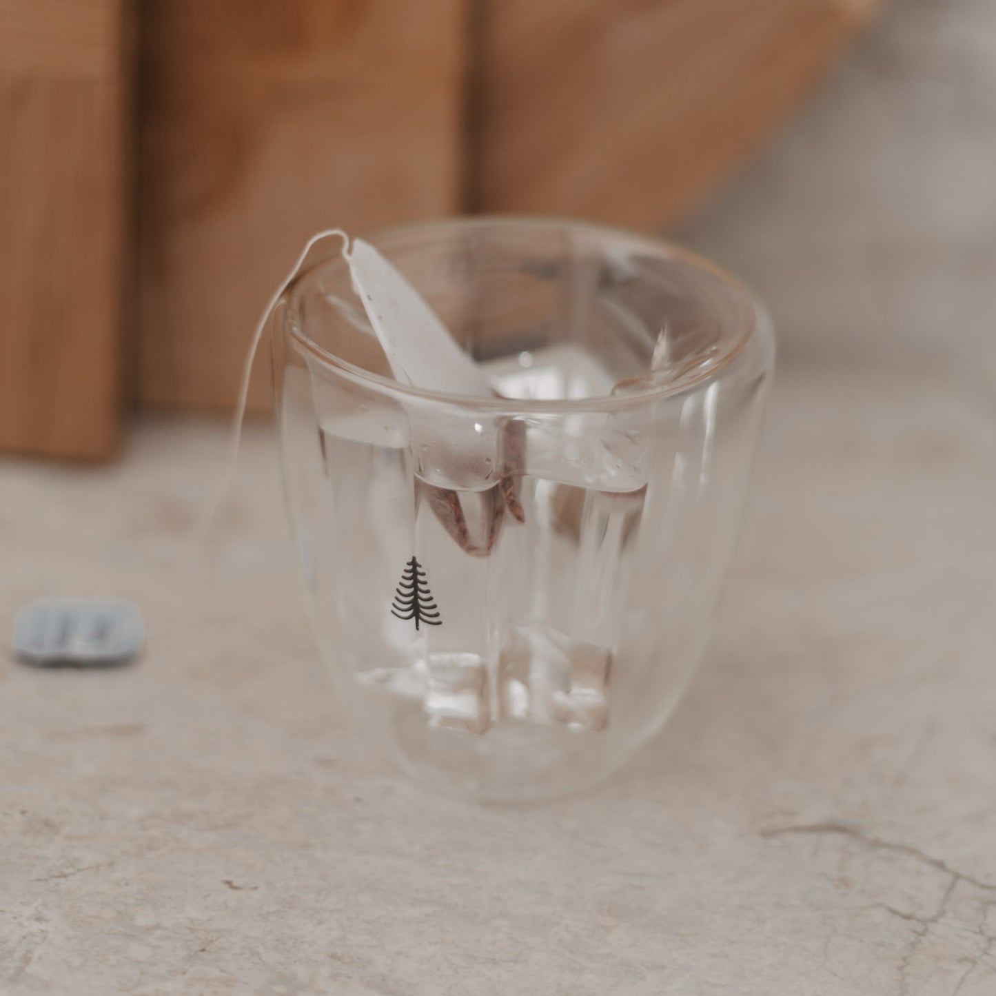 Heißes Getränk mit Teebeutel im doppelwandigen Tannenglas, hitzebeständig und elegant.