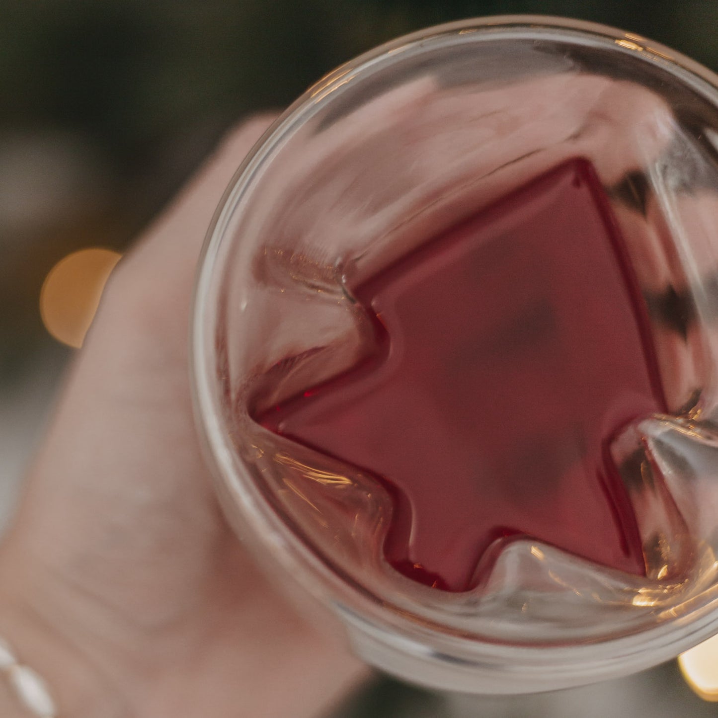 Detailansicht des doppelwandigen Glases mit rotem Getränk, Baumform schräg sichtbar.