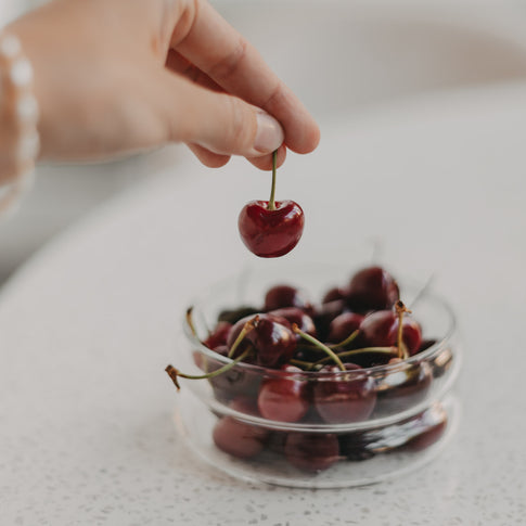 Hand hält Kirsche – Hand greift nach Kirsche aus der Bubbles-Schale klein, ideal für Snacks oder Obst.