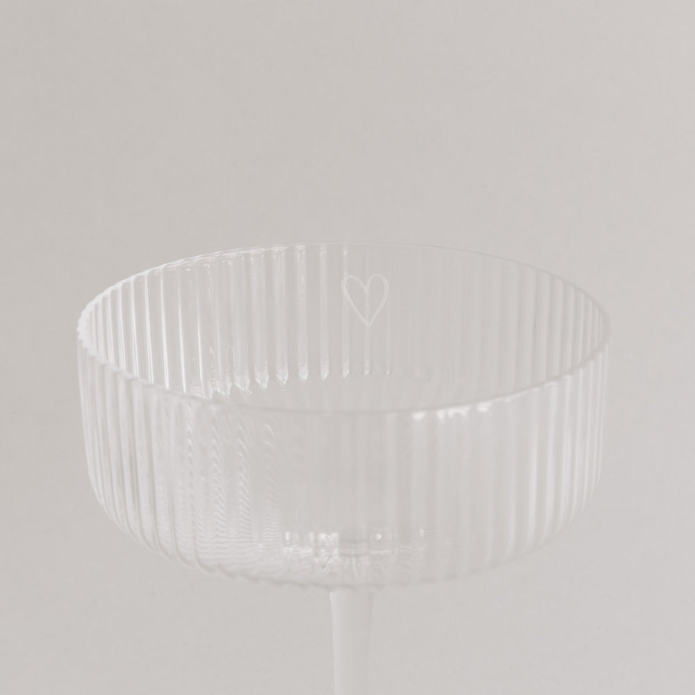 Nahaufnahme des Randes eines Champagnerglases mit graviertem Herz.