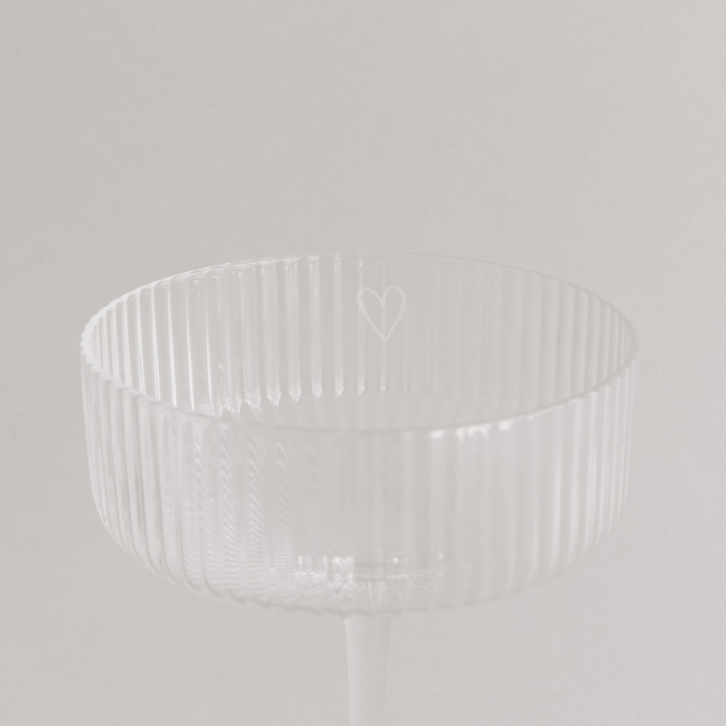 Nahaufnahme des Randes eines Champagnerglases mit graviertem Herz.