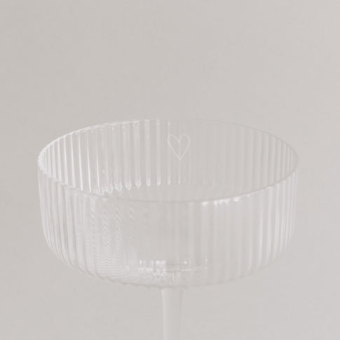 Nahaufnahme des Randes eines Champagnerglases mit graviertem Herz.