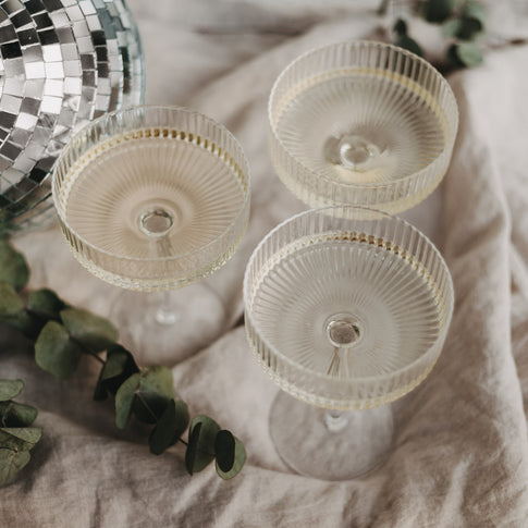 Drei gefüllte Champagnergläser mit Disco-Kugel und Eukalyptus – perfekte Szenerie für eine kleine Auszeit.