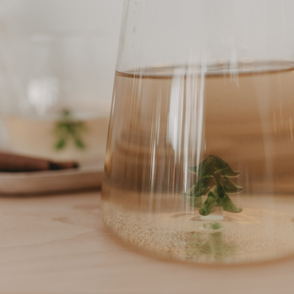 Nahaufnahme der gefüllten Karaffe mit Tannenbaum-Detail – warmes Licht und festliche Atmosphäre.