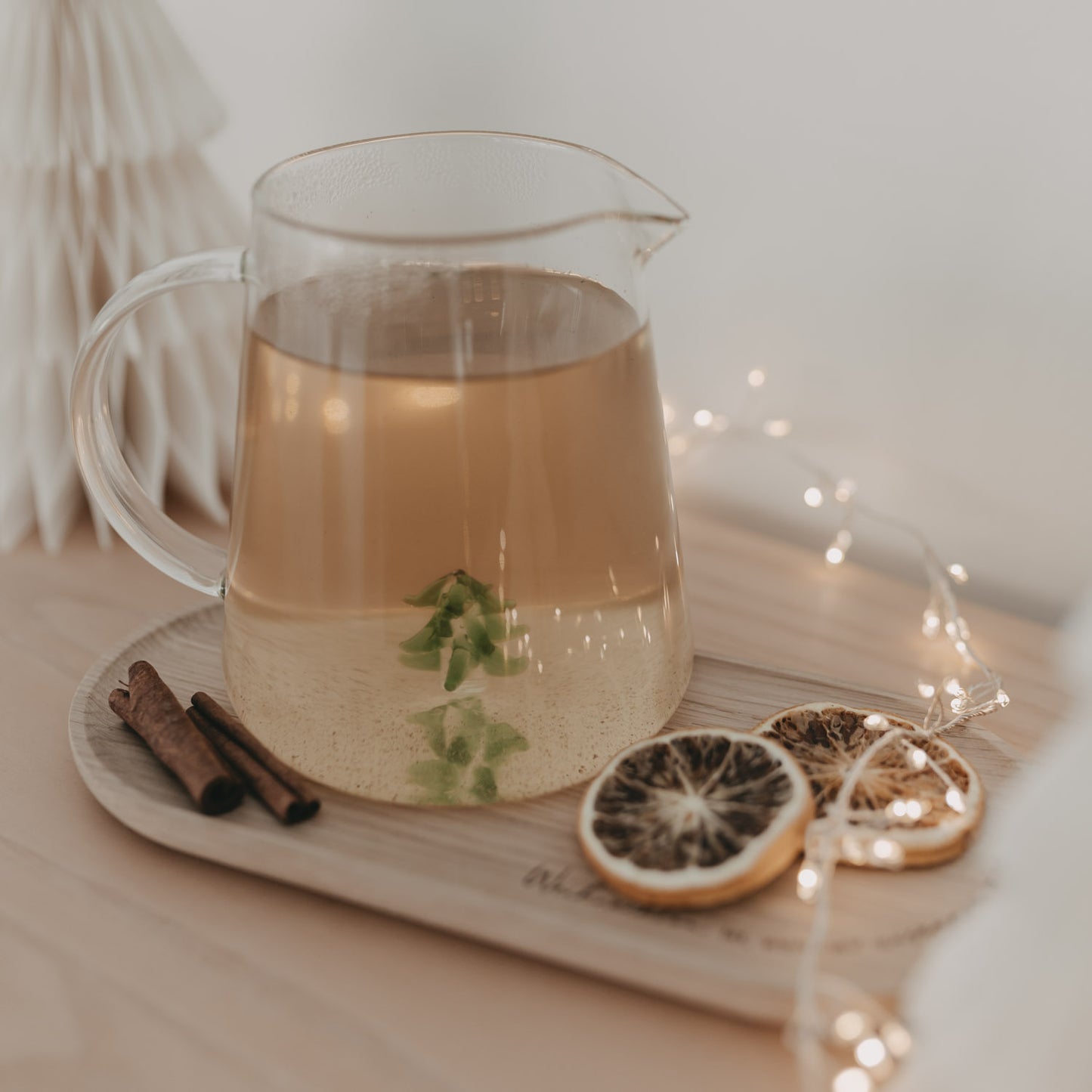 Karaffe mit Tee und Tannenfigur, dekoriert mit Trockenfrüchten und Zimt – festliche Stimmung pur.