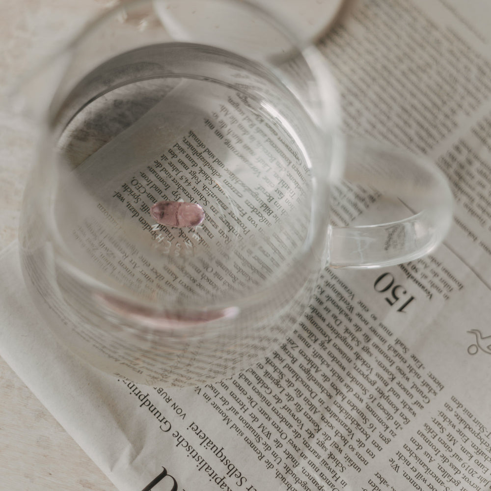Blick in die Karaffe mit Wasser, durch das sich die rosa Herzfigur am Boden abzeichnet.