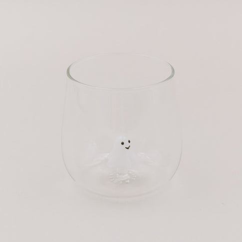 Glas mit kleiner weißer Geistfigur als 3D-Detail am Glasboden, hell und minimalistisch inszeniert