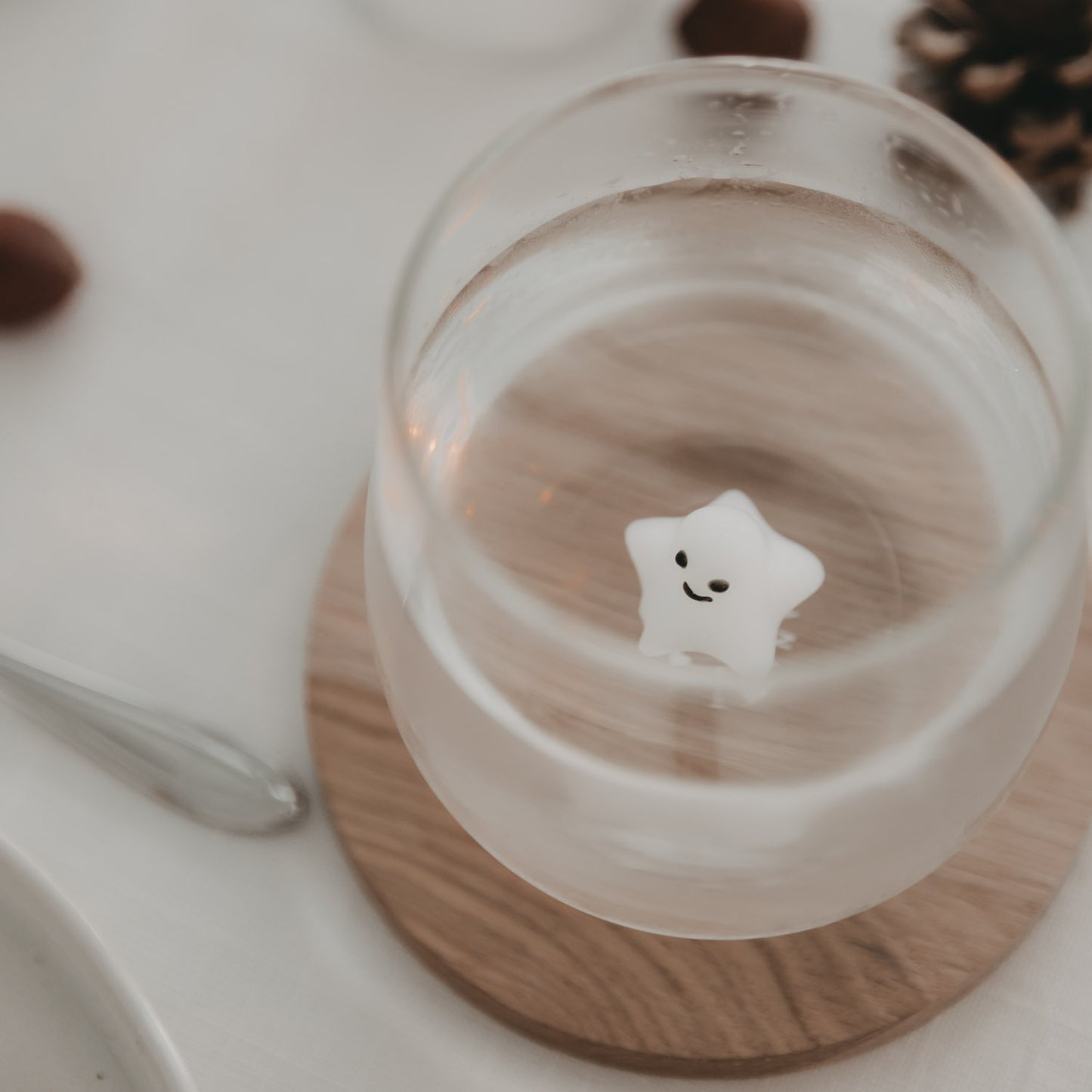 Von oben fotografiertes Trinkglas mit 3D-Sternfigur auf einem runden Holzuntersetzer