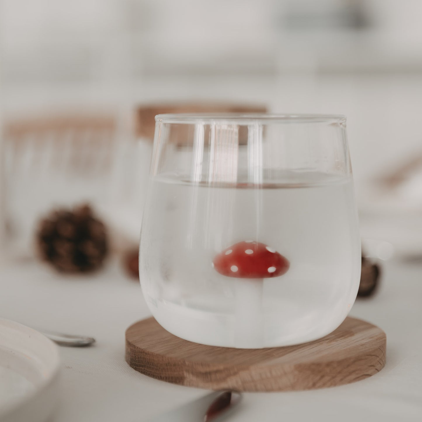 Trinkglas mit Fliegenpilz gefüllt mit Wasser – der Pilz wirkt im Glas optisch schwerelos und magisch