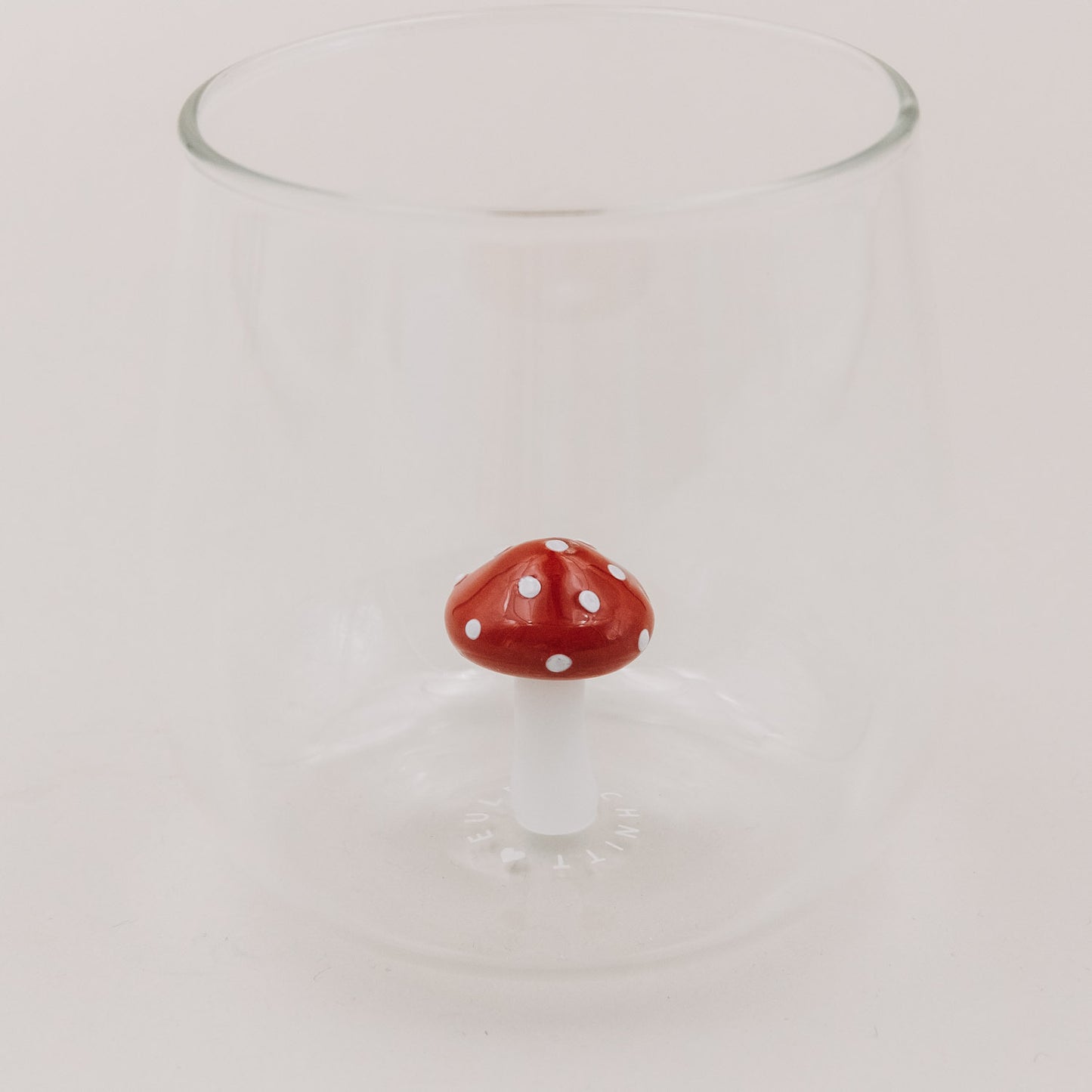 Trinkglas mit schwebender Pilzfigur – der rote Fliegenpilz setzt einen verspielten Akzent im Glasboden