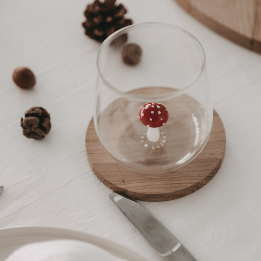 Trinkglas mit schwebender Pilzfigur – der rote Fliegenpilz setzt einen verspielten Akzent im Glasboden