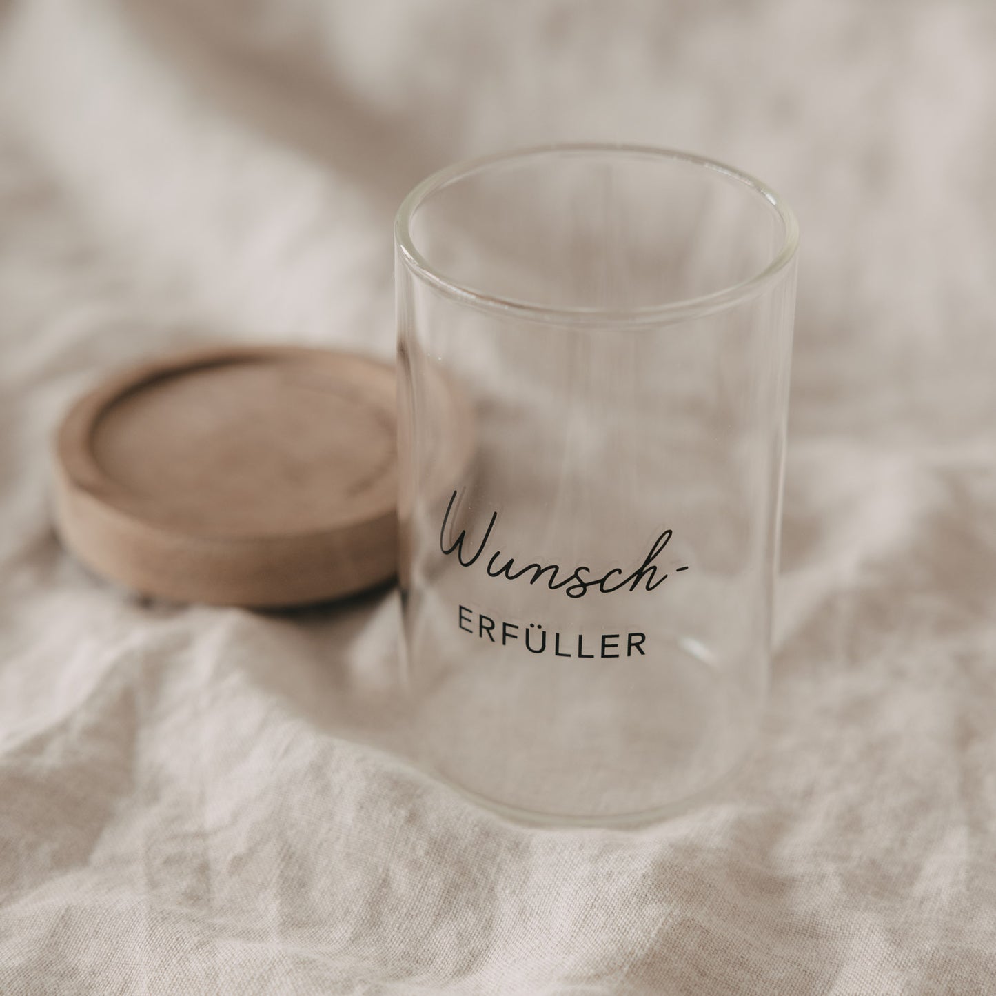Minivorratsglas „Wunscherfüller“ mit abgenommenem Holzdeckel auf hellem Stoff