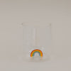 Klares Trinkglas mit buntem Regenbogen am Boden, schlichtes Design freigestellt
