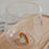 Detailaufnahme Glas mit buntem Regenbogen am Boden, modernes Trinkglas auf Holztablett