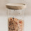 Detailaufnahme eines Vorratsglases mit schwarzen Herzen, gefüllt mit Müsli und verschlossen mit Holzdeckel.