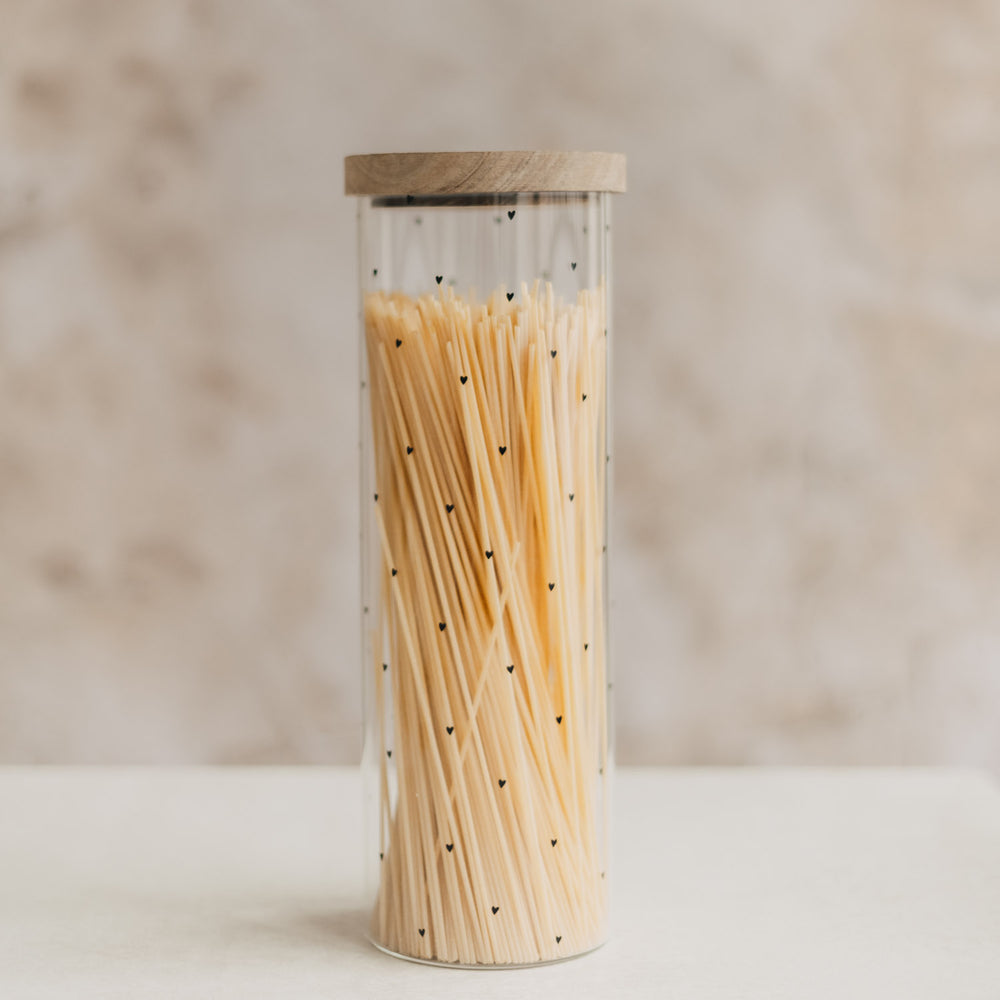 Hohes Vorratsglas mit schwarzen Herzen und Holzdeckel, gefüllt mit Spaghetti.