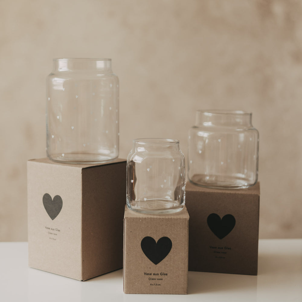 Drei Glasvasen mit Herzprint in verschiedenen Größen auf Geschenkboxen arrangiert
